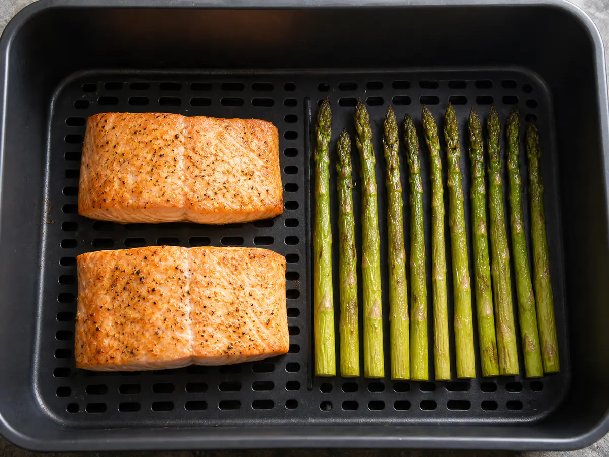 Draufsicht auf Lachs und Spargel als gemeinsam zubereitete Heißluftfritteusen-Mahlzeit.