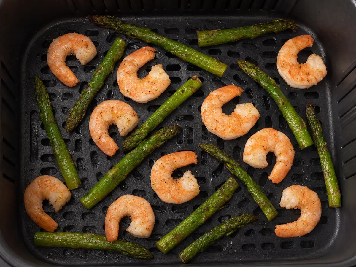Vue de dessus de crevettes et asperges cuit à la friteuse à air comme repas dans un seul panier.
